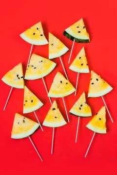 A lots of triangular pieces of ice cream on a stick of ripe yellow watermelon Foto stock
