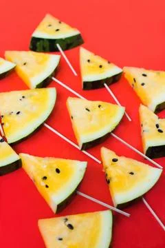 A lots of triangular pieces of ice cream on a stick of ripe yellow watermelon 库存照片