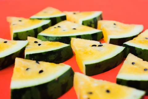 A lots of triangular pieces of ripe yellow watermelon on red background Foto stock