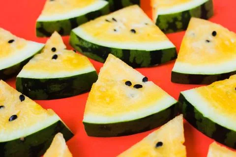A lots of triangular pieces of ripe yellow watermelon on red background 写真素材