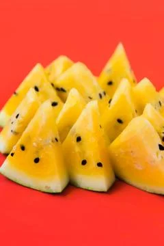A lots of triangular pieces of ripe yellow watermelon on red background Foto stock