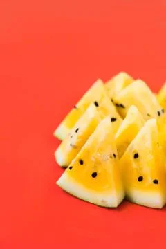 A lots of triangular pieces of ripe yellow watermelon on red background 写真素材