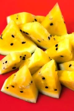 A lots of triangular pieces of ripe yellow watermelon on red background 스톡 사진