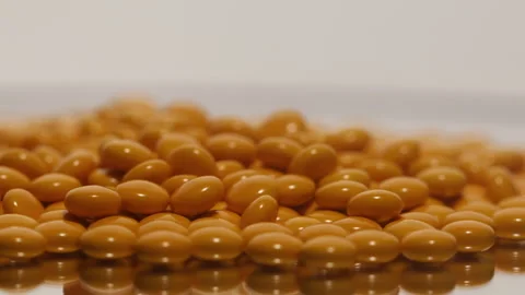 Lots of yellow pill capsules on a rotating stand. Stock Footage 250083708