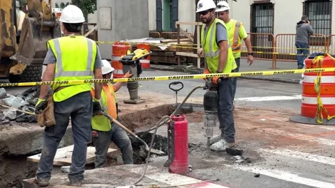 Loud jackhammer construction workers working job site hardhats orange cones NYC Stock Footage 162593304