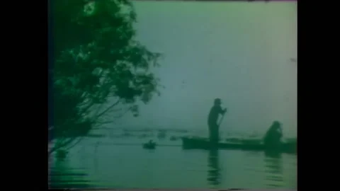 LOUISIANA - 1974 - Men catch crawfish from their pirogue in a Louisiana bayou. Stock Footage 296397341