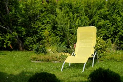 Lounge chair and straw hat on sunny lawn. Stock Photos