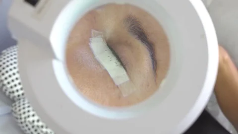 Loupe сlose-up of master make long lashes. Eyelash extension in beauty studio. Stock Footage 75709664