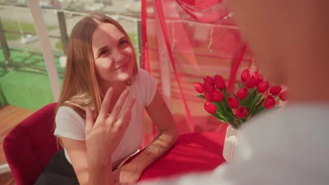 Love asks her, Heartfelt proposal captured in lively cafe environment, Woman Stock Footage 325213855