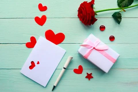 Love composition - red rose, gift box and greeting card on blue wooden backgr Stock Photos