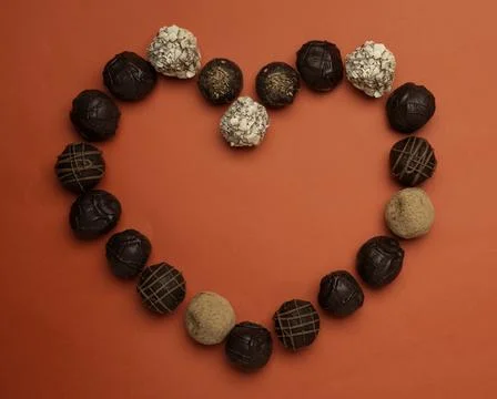 Love concept image of heart shape made of chocolate truffles on red paper tex Foto stock