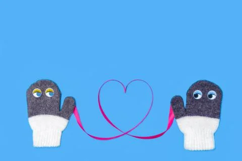 Love concept for Valentine's Day. Mittens with eyes hold ribbon that forms heart Stock Photos