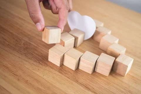 Love connection concept. Someone assembles wood blocks to  be heart shape. Stock Photos