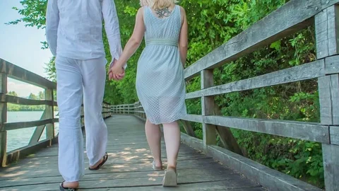 Love couple is walking on a wooden path around a lake Stock Footage