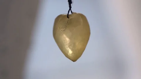 Love crystal heart shaped pendulum moving with the wind in slow motion Video stock 76807632