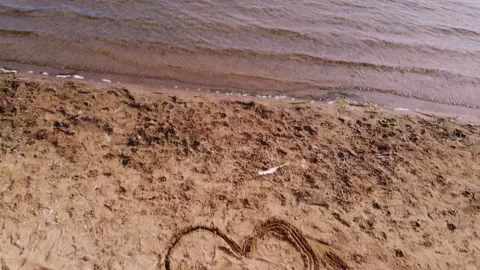 Love heart drawing in sand on lake side beach Stock Footage 346771663
