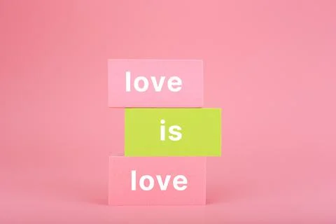 Love is love written on stack of yellow and pink rectangles on pink background Stock Photos