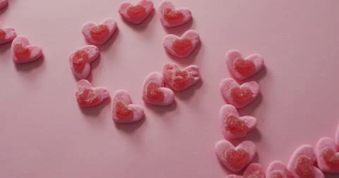 Love text of heart shape sweets on pink background at valentine's day Vídeo Stock 343237482