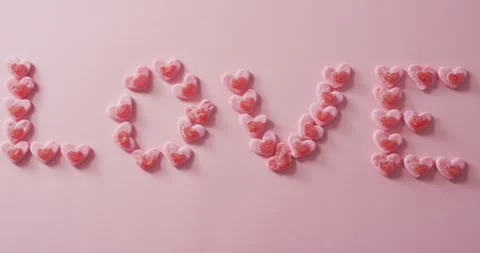 Love text of heart shape sweets on pink background at valentine's day Vídeo Stock 344315433