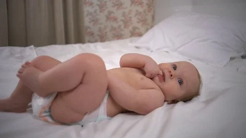 Lovely baby gitl lying on the bed with finger in the mouth slow motion Video stock 74244769