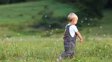 Lovely baby have fun, run to catch the soap bubbles, water baloons Stock Footage