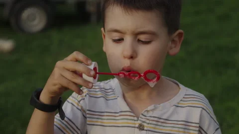 Lovely boy doing soap balloons outside in the garden . Stock Footage 245752175