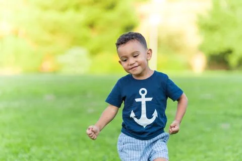Lovely boy playing and running in a park outdoors. Stock Photos