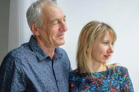 Lovely Couple with Age Difference Looking though Opened Window inside the House Stock Photos