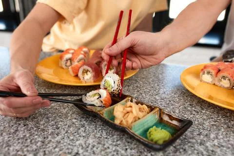 Lovely couple having fun while eating sushi rolls at home, croped shote, hands Stock Photos