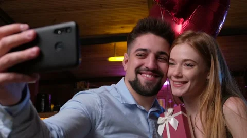 Lovely couple making a selfie while holding valentines gift and air balloons Stock Footage 148613093