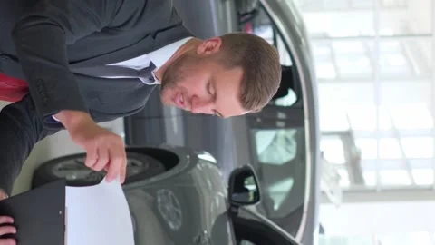 A lovely couple is talking to a manager while buying a car at a car dealership Stock Footage 250351543