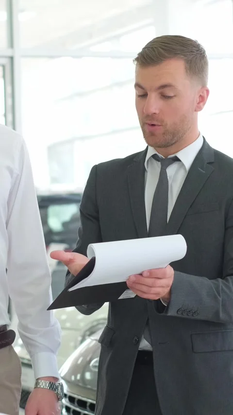 A lovely couple is talking to a manager while buying a car at a car dealership Stock-Footage 250386101