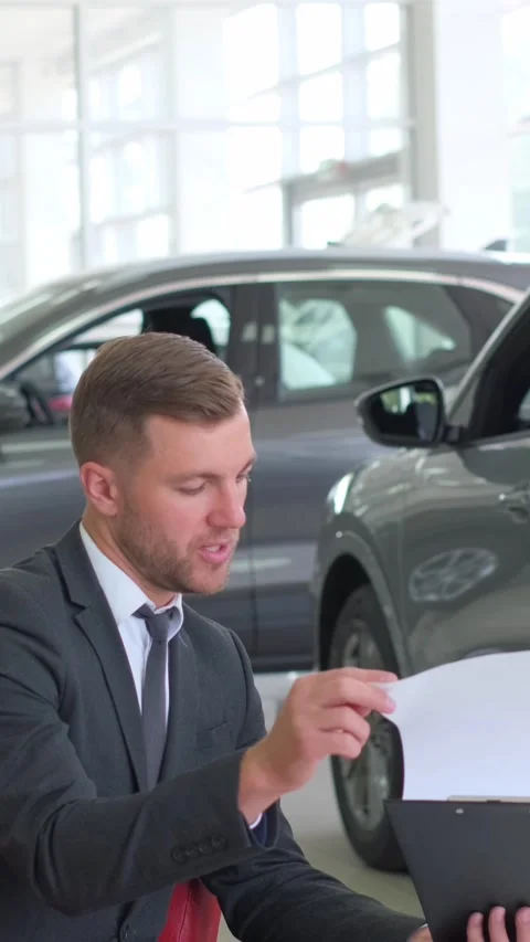 A lovely couple is talking to a manager while buying a car at a car dealership Stock-Footage 250386866