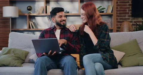 Lovely happy in high spirits young man and woman sitting together on sofa couch Stock Footage 225647219