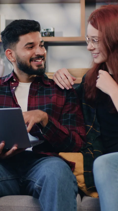 Lovely happy in high spirits young couple sitting together on sofa couch at home Stock Footage 325625500