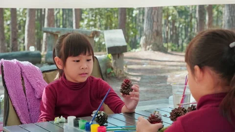 Lovely sisters paint on pine cones to decorate the Christmas tree.  Stock Footage 227988534