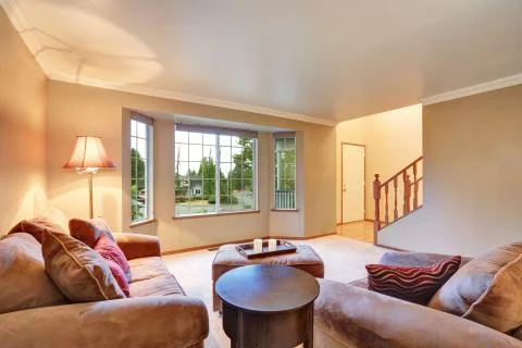 Lovely sitting room with mocha sofas and ottoman. Also carpet floor, beige wa Stock Photos
