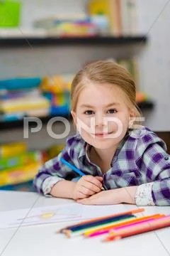 Lovely smiling little girl with blond hair sitting at white table Stock Photos