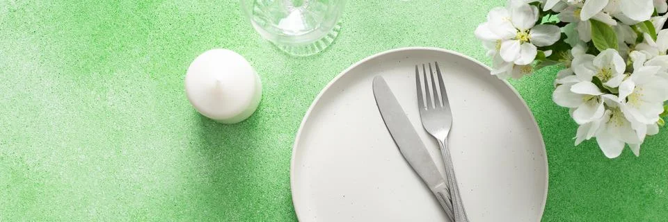 A lovely spring table setting features a white plate, silverware, and elegant Stock Photos
