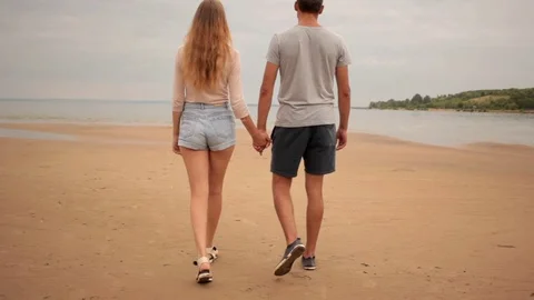 Lovers are holding hands and walk on sea beach 스톡 동영상 78038191