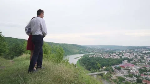 Lovers are holding hands approaching to edge of cliff, looking on city view Stock Footage 221017839