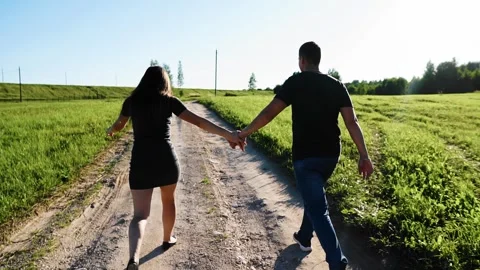 Lovers are running along a path in nature. The guy runs after his girlfriend Stock Footage 304997473