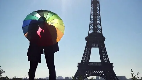 Lovers behind colored umbrella in front of Eiffel tower in Paris Stock Footage 69181963
