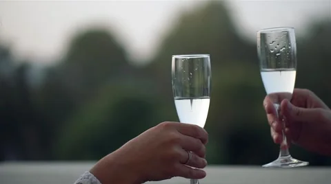 Lovers clink glasses at a restaurant in the open air on their wedding day. Close Video stock 68785960