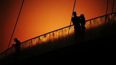 Lovers Couple At Dusk On Bridge Back Lit Silhouette. Stock Footage 74332047