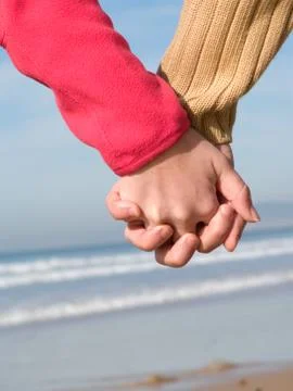 Lovers couple holding hands on beach at winter Stock Photos