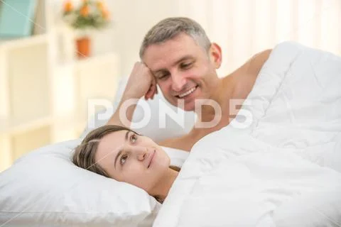The lovers couple lay on the bed and look Stock Photos