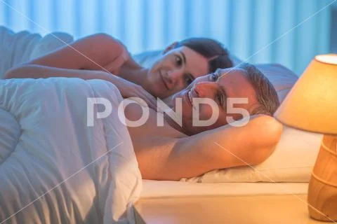 The lovers couple lie on the bed. Evening night time Stock Photos