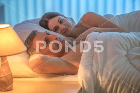The lovers couple lie on the bed. Evening night time Stock Photos