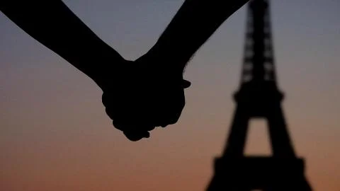 Lovers hand in hand in front of Eiffel tower Paris, silhouettes sunset Stock Photos